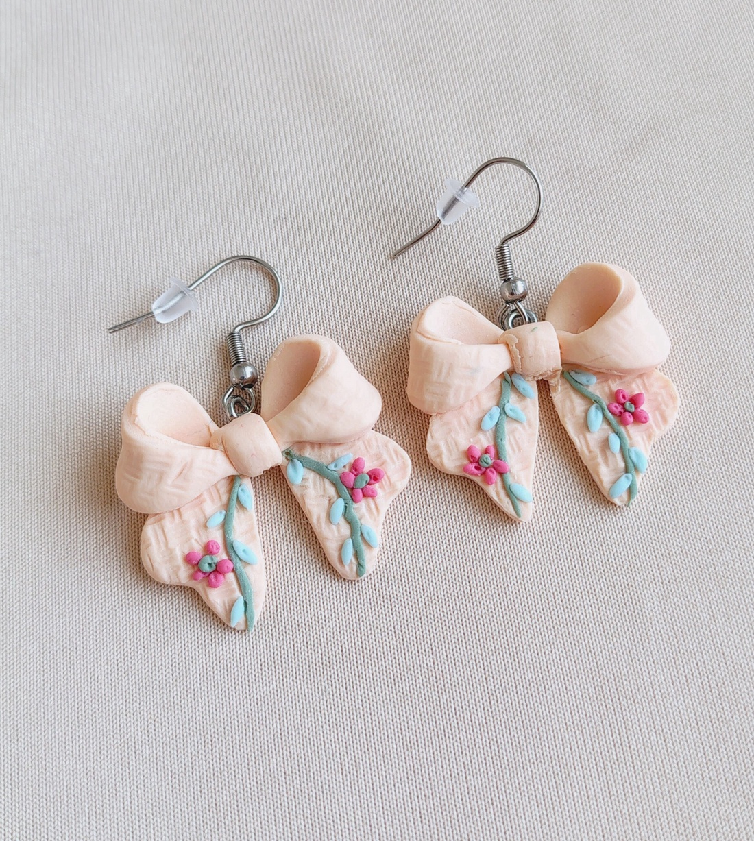 Cercei fundiță din lut polimeric, textură brodată � culoarea piersicii  - bijuterii - cercei - cercei cu figurine - Artynos.ro