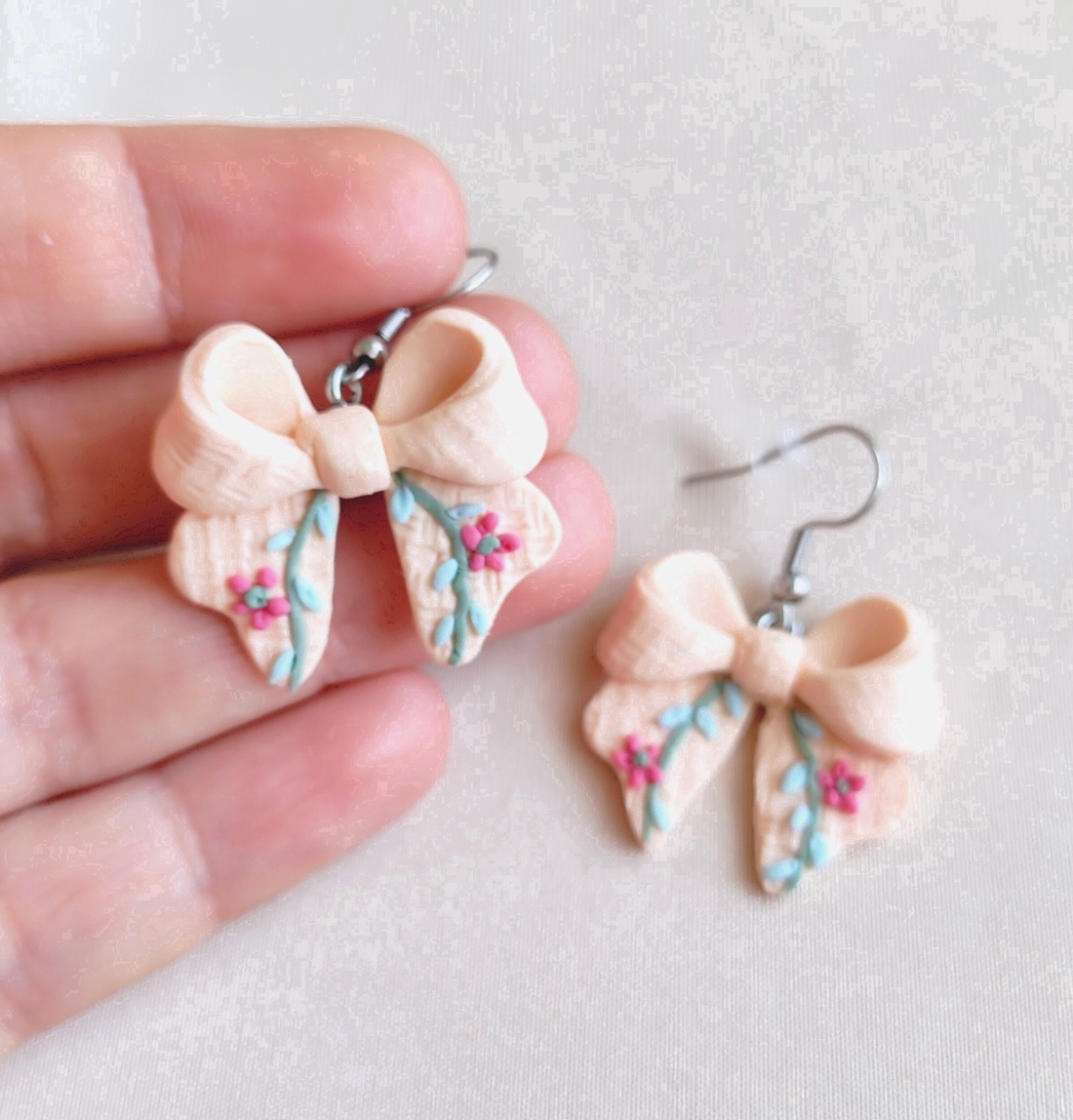 Cercei fundiță din lut polimeric, textură brodată � culoarea piersicii  - bijuterii - cercei - cercei cu figurine - Artynos.ro