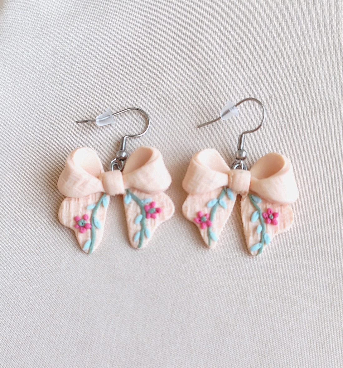 Cercei fundiță din lut polimeric, textură brodată � culoarea piersicii  - bijuterii - cercei - cercei cu figurine - Artynos.ro
