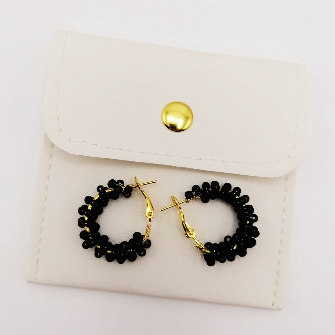 Cercei rotunzi aurii cu pietre negre, cu plic din piele alb - bijuterii - cercei - cercei din mărgele - Artynos.ro