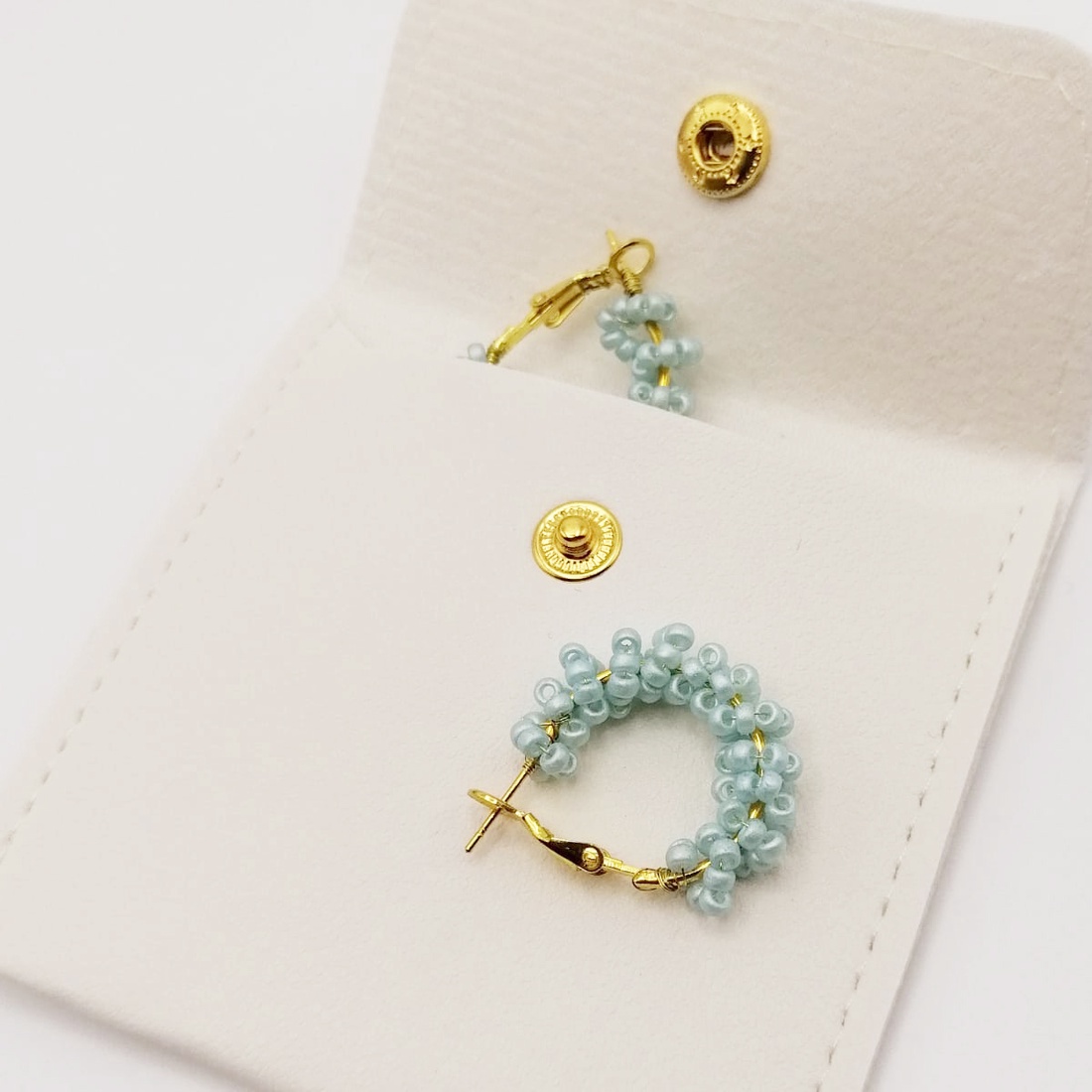 Cercei rotunzi aurii cu pietre albastre, cu plic din piele alb - bijuterii - cercei - cercei din mărgele - Artynos.ro