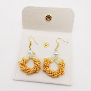 Cercei rotunzi din pietre din nisip negre/oranj si perla alba sintetica  model elegant, cu plic de piele alba - bijuterii - cercei - cercei din mărgele - Artynos.ro