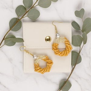 Cercei rotunzi din pietre din nisip negre/oranj si perla alba sintetica  model elegant, cu plic de piele alba - bijuterii - cercei - cercei din mărgele - Artynos.ro